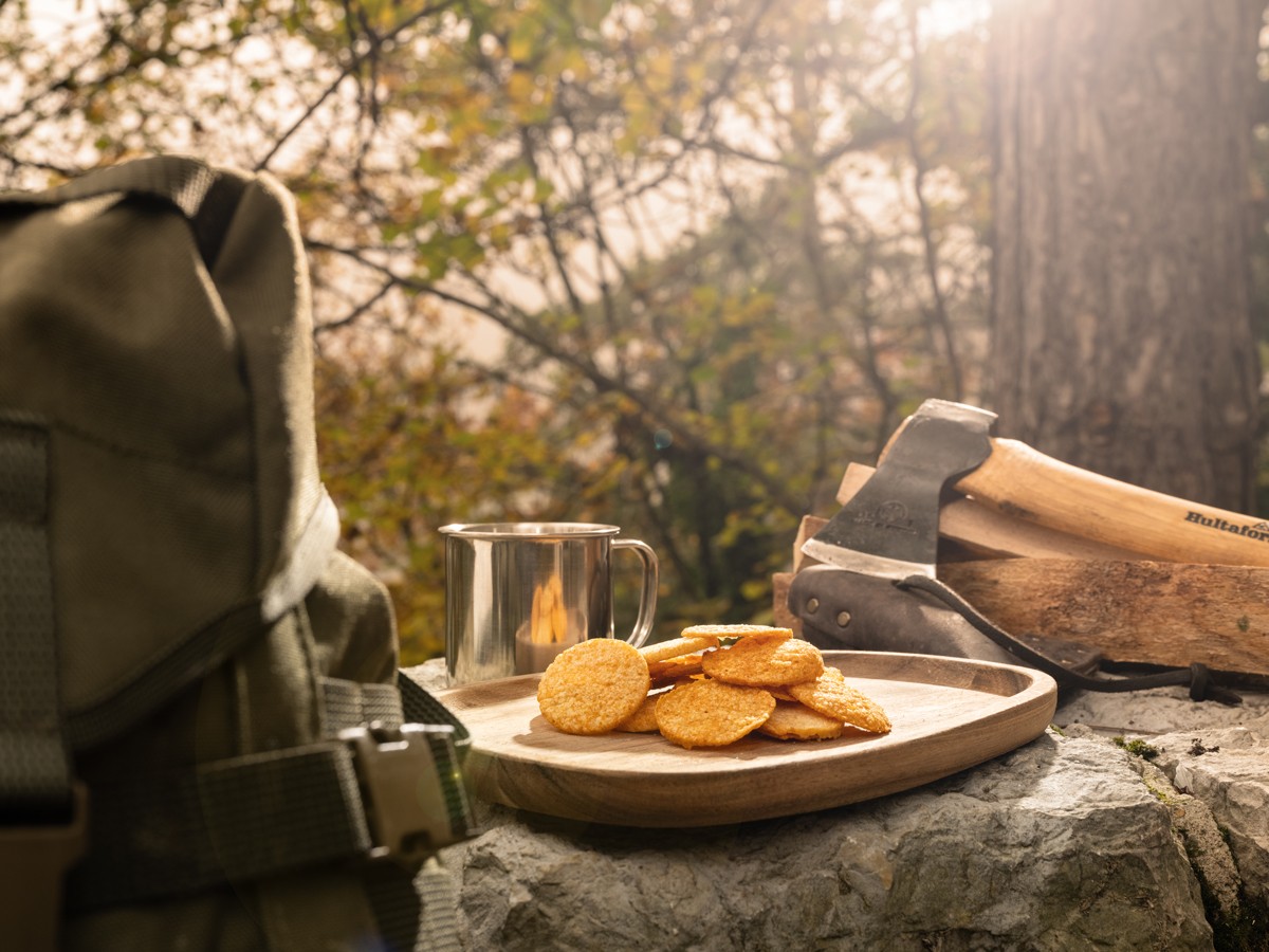 Chips protéinées Wildcrisps paprika posées en forêt avec hache et tasse